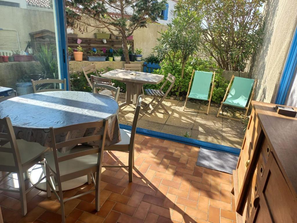 d'une terrasse avec 2 tables et des chaises. dans l'établissement Appartement à Noirmoutier, proche plage, animaux admis, parking - FR-1-823-140, à Noirmoutier-en-l'lle