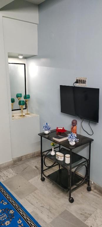 a living room with a black table with a flat screen tv at The Grasshopper's nest in kolkata
