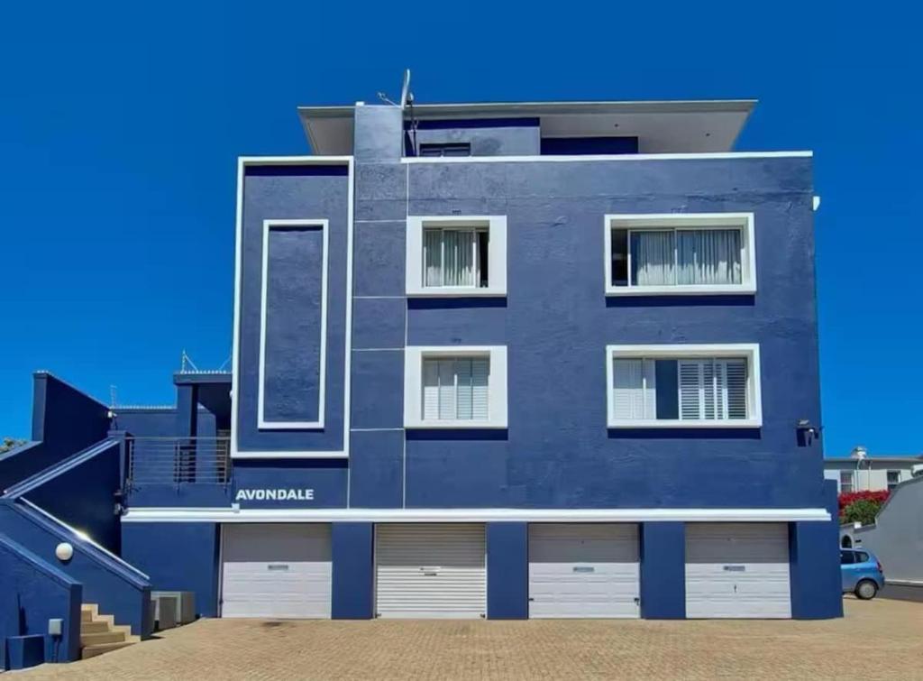 a blue building with white doors and windows at Cape Town Apartment, Sea View in Cape Town