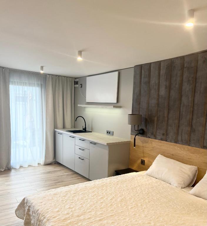 a bedroom with a bed and a sink and a kitchen at Pokoje Gościnne Lidka in Dziwnów