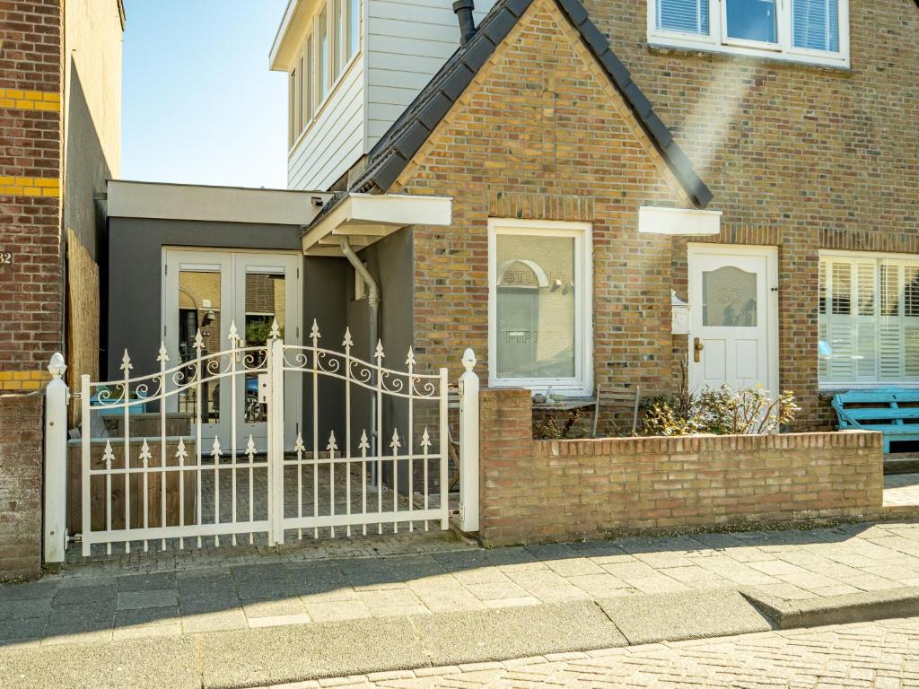 una recinzione bianca di fronte a una casa di mattoni di Studio Pipper a Zandvoort