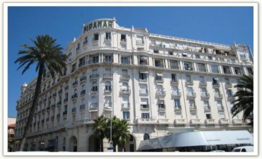 un grand bâtiment blanc avec un palmier en face dans l'établissement Croisette Luxury sea-view studio, à Cannes