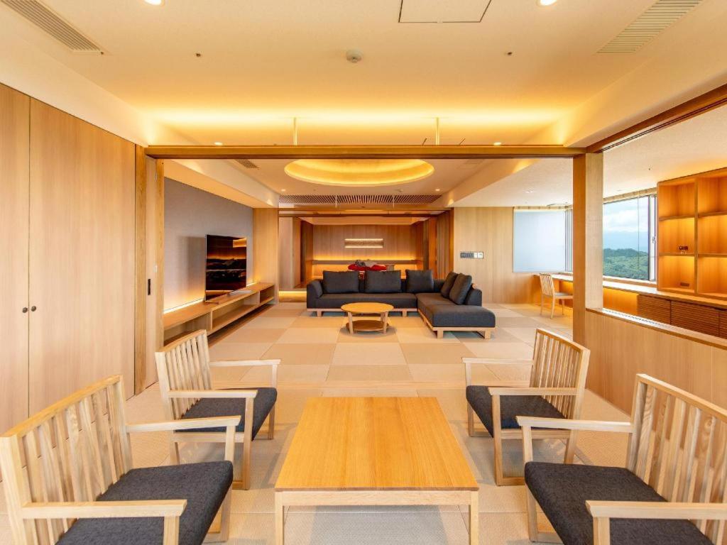 a living room with a couch and a table and chairs at Hotel Kogure in Shibukawa
