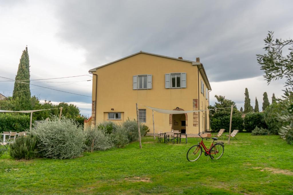 a house in a yard with a bike in the grass at Podere Bellavista - Agriturismo Bella Valle in Vada