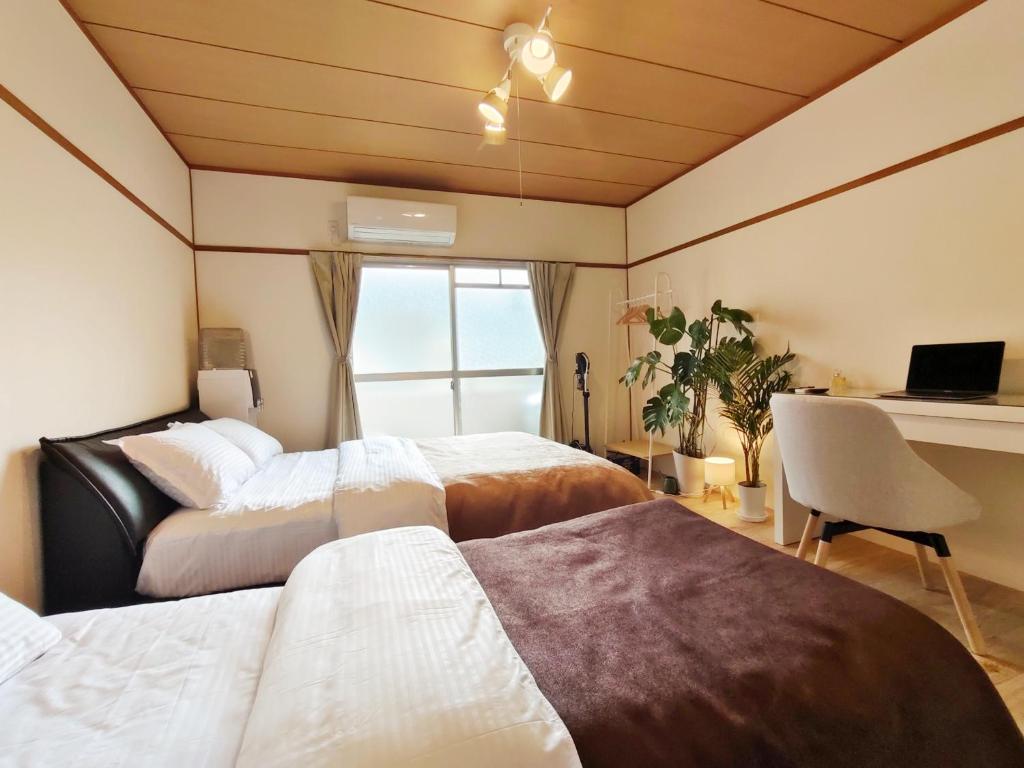 una camera da letto con due letti e una scrivania con un computer di ゲストハウスDiDi a Tokushima