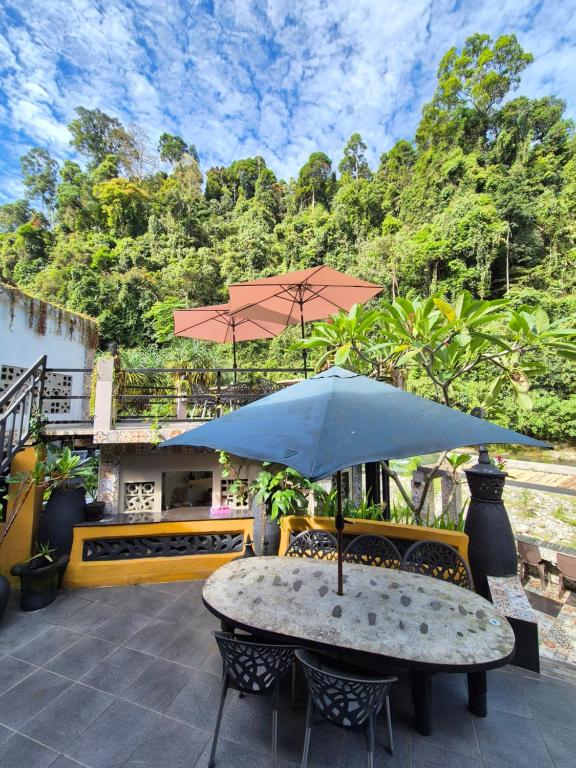 a table with an umbrella on a patio at Jungle Inn Bukit lawang in Bukit Lawang