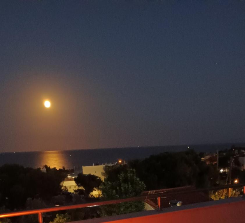 a full moon over the ocean at night at Salty Sea Breeze in Artemida