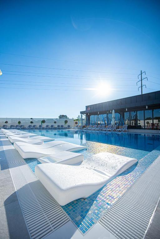 ein Schwimmbecken mit weißen Liegestühlen und Stühlen in der Unterkunft VILA ODISEA in Baile Felix