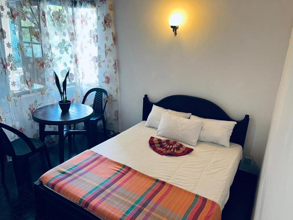 a small bedroom with a bed with a table and a table at Mystique Hideout in Kandy