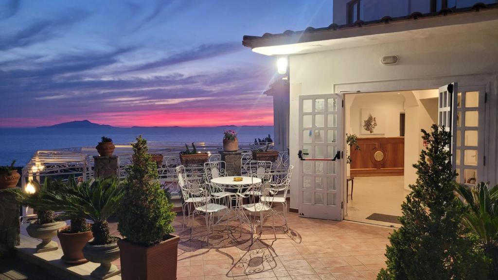 a patio with a table and chairs with a view of the ocean at Hotel Dania in Sorrento