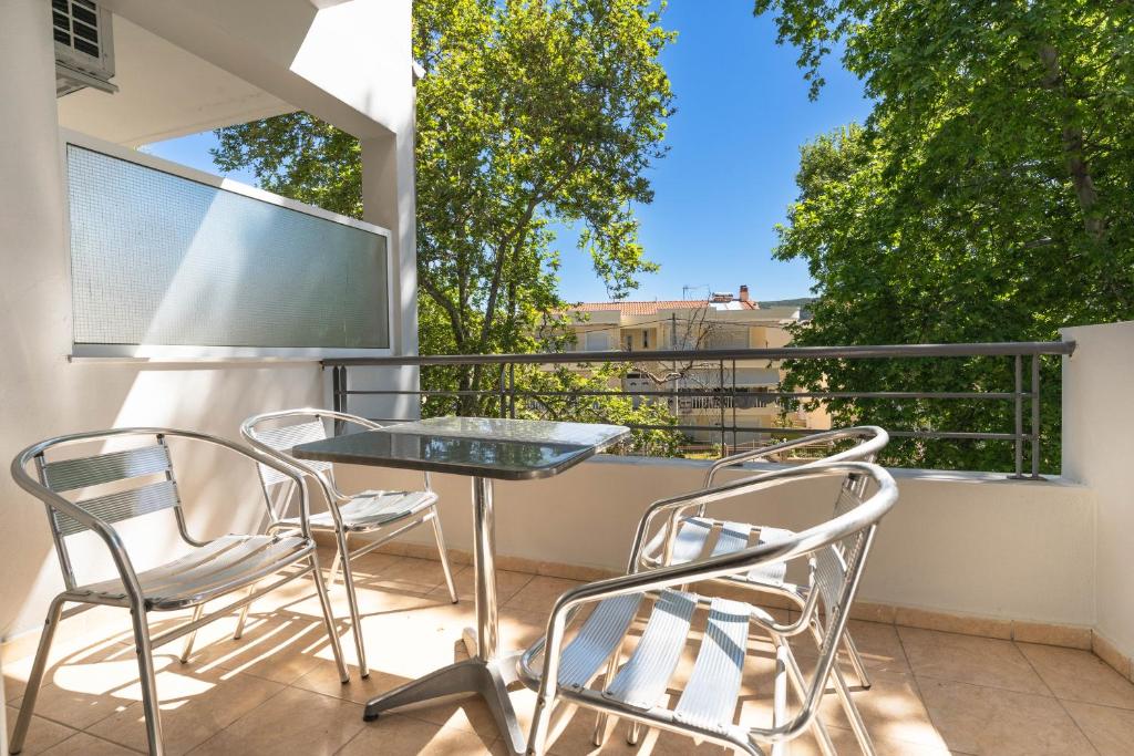 a balcony with a glass table and two chairs at Kipos Resort in Nea Peramos