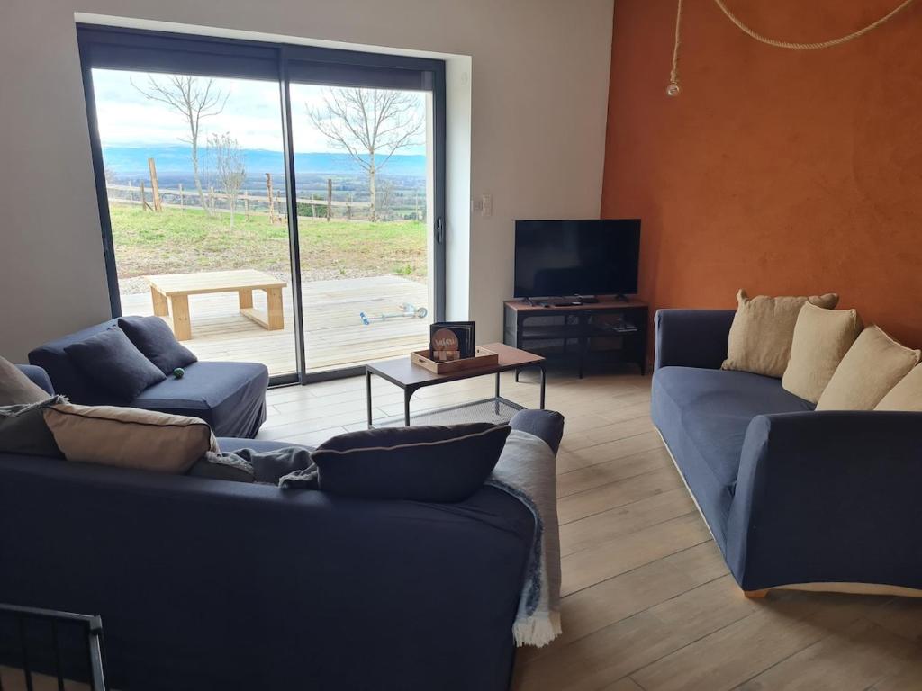 - un salon avec deux canapés bleus et une grande fenêtre dans l'établissement Maison de 2 gites privatifs et communicants 14 places, à Pouilly-les-Feurs