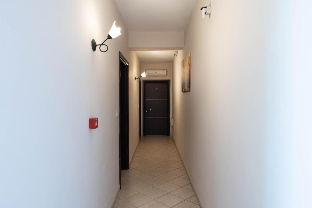 a hallway with a white wall and a black door at Kipos Resort in Nea Peramos