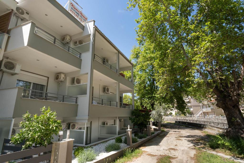 an apartment building with balconies and a tree at Kipos Resort in Nea Peramos