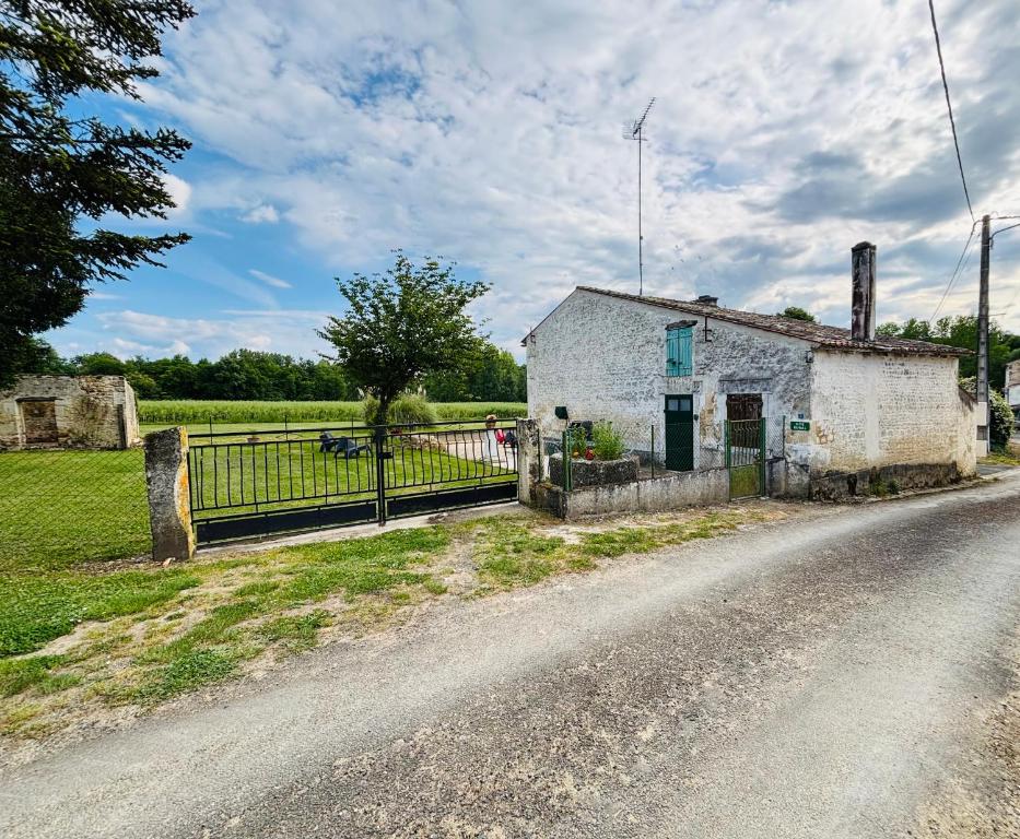 un vieux bâtiment blanc sur le côté d'une route dans l'établissement roumeneche THERMALISME jonzac au sejour ou a la semaine, à Marignac