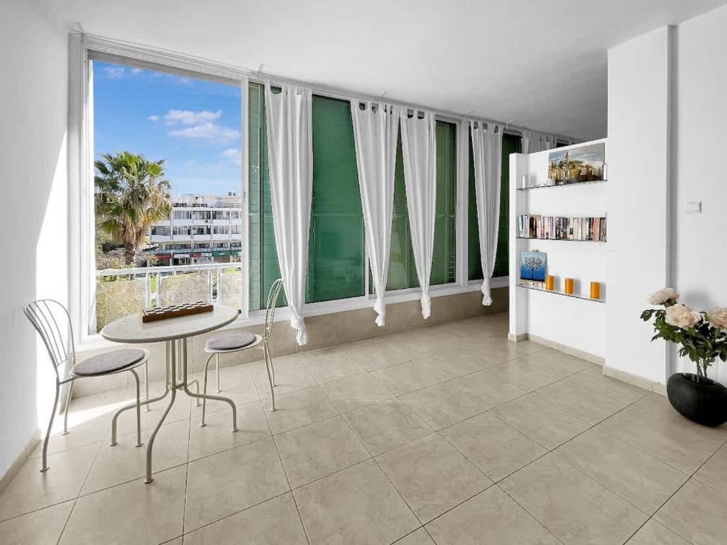 a room with a table and chairs and a large window at Elegant Beachside Apartment in Herzliya B