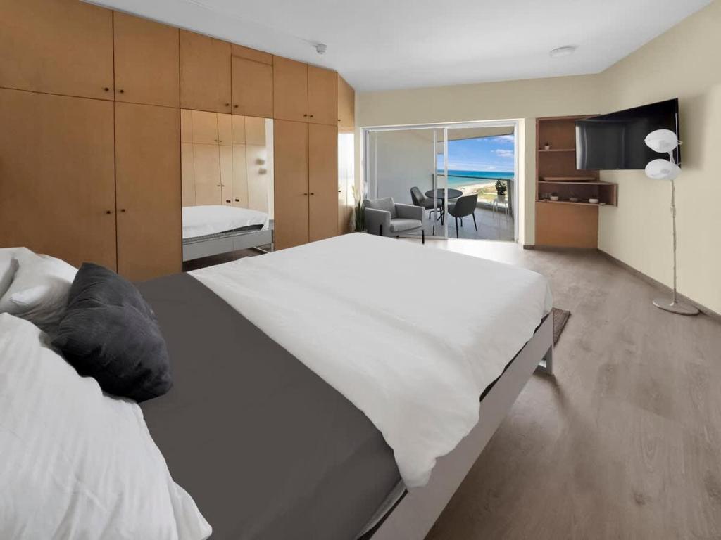 a bedroom with a large white bed and a living room at The Sharon Secret Pearl in Herzliya B