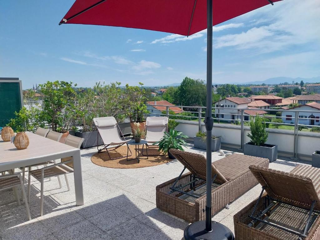 un patio avec une table, des chaises et un parasol dans l'établissement Beau T4 de 95 m2 avec terrasse sur Anglet, à Anglet