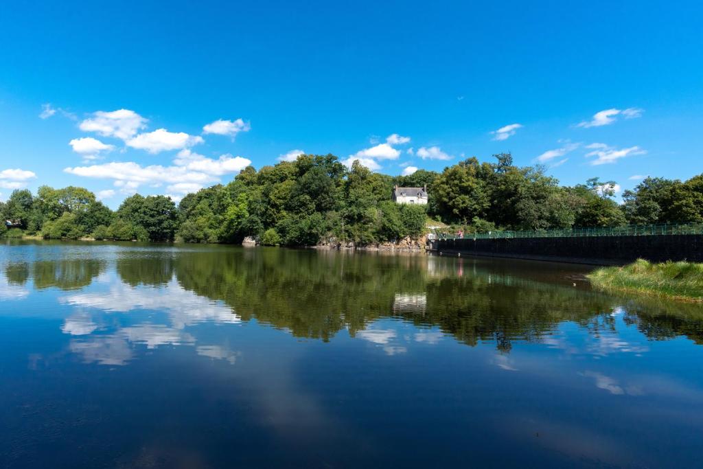 une rivière avec des arbres et une maison au loin dans l'établissement Maison du barragiste, à Allineuc