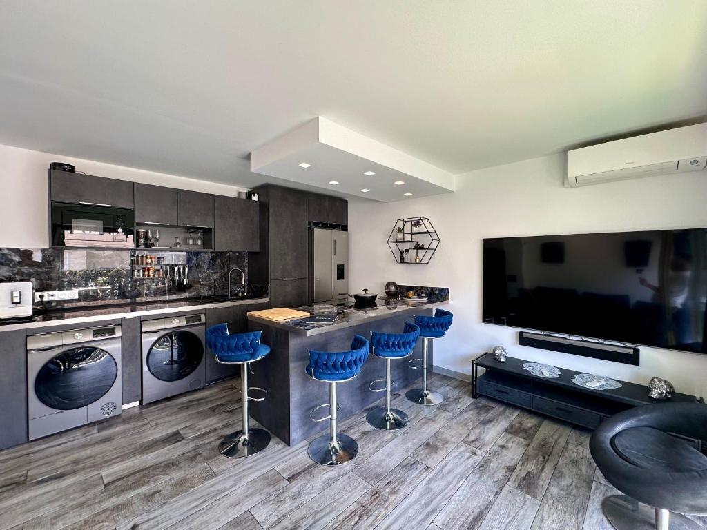 une cuisine avec des tabourets de bar bleus et une grande télévision dans l'établissement Le Patio Bleu, à Vallauris