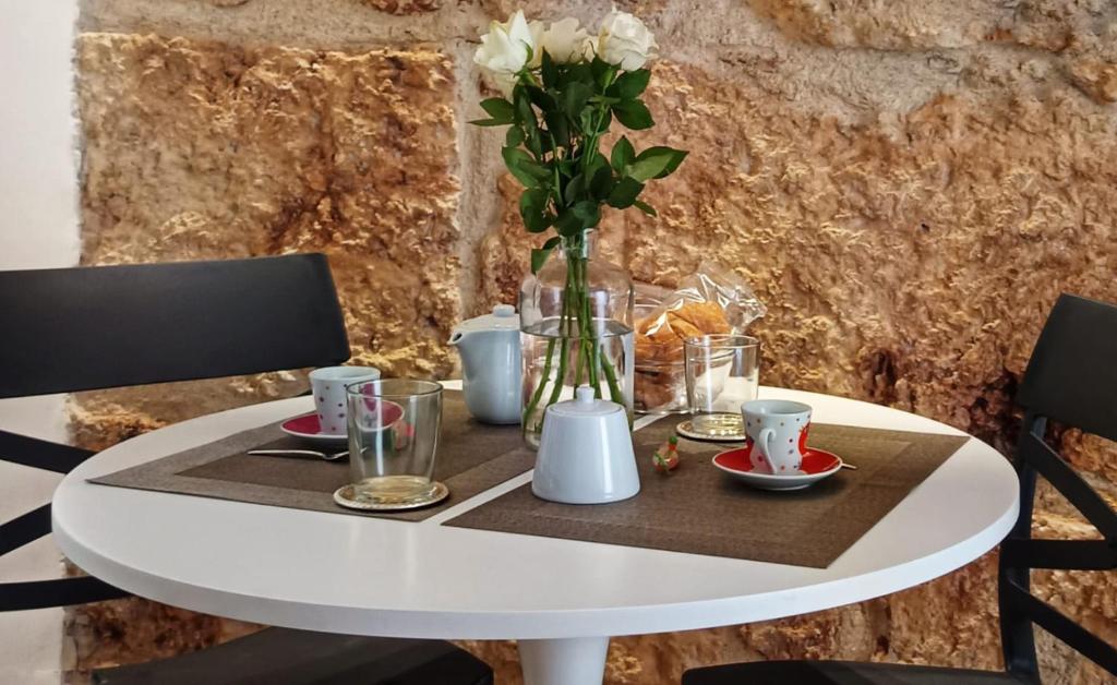 ein weißer Tisch mit einer Vase Blumen drauf in der Unterkunft Dimora al Capo in Palermo