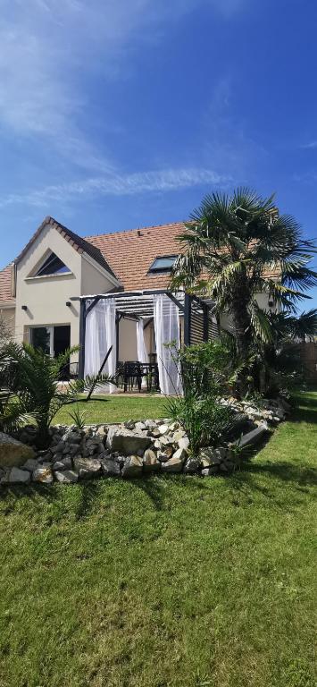 une maison avec un palmier et un mur en pierre dans l'établissement Véro et Domi, à Roézé-sur-Sarthe