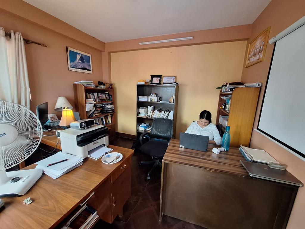 un ufficio con una persona seduta a una scrivania con un computer portatile di Purposeful Travel Planner- Homestay, Culture & Volunteering a Patan