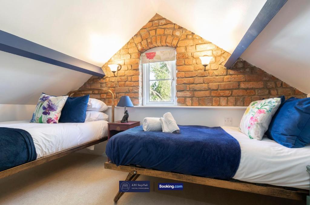 ein Schlafzimmer im Dachgeschoss mit zwei Betten und einem Fenster in der Unterkunft Pet Friendly Cottage By KBS Stayhub Short Lets & Serviced Accommodation Stonehouse With Log Fire, Parking in Gloucestershire
