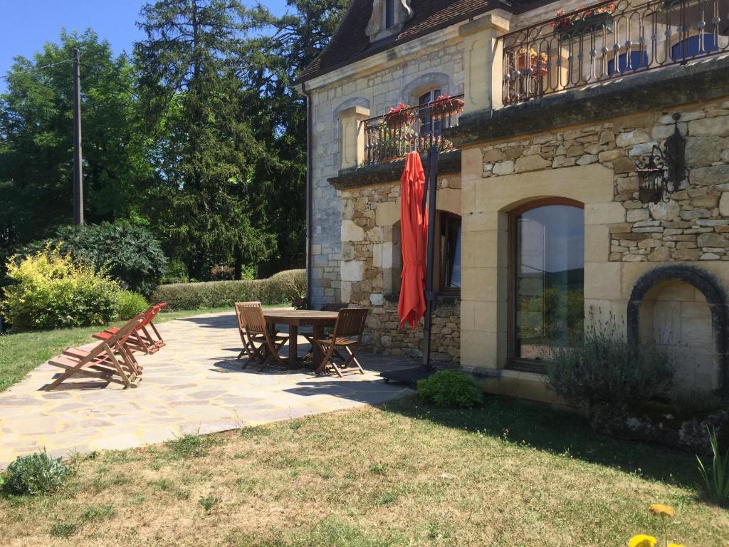 patio ze stołem i krzesłami obok budynku w obiekcie Domaine du Fraysse Le Cèdre un havre de paix w mieście Saint-Cybranet