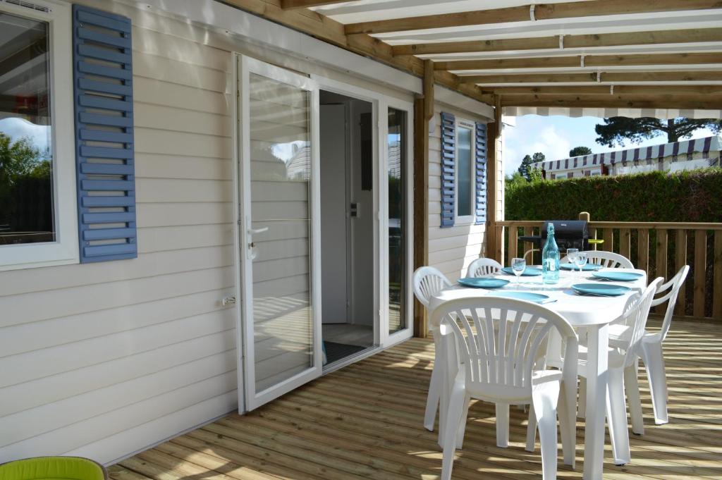 a white table and chairs on a deck with a door at Beau mobilhome La Palmyre 4 étoiles in Les Mathes