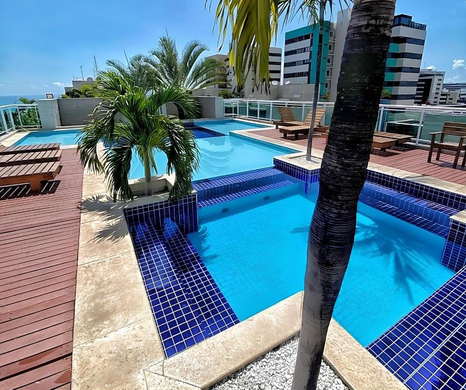 a swimming pool on the roof of a building with palm trees at Areialoka Apartamento in Maceió