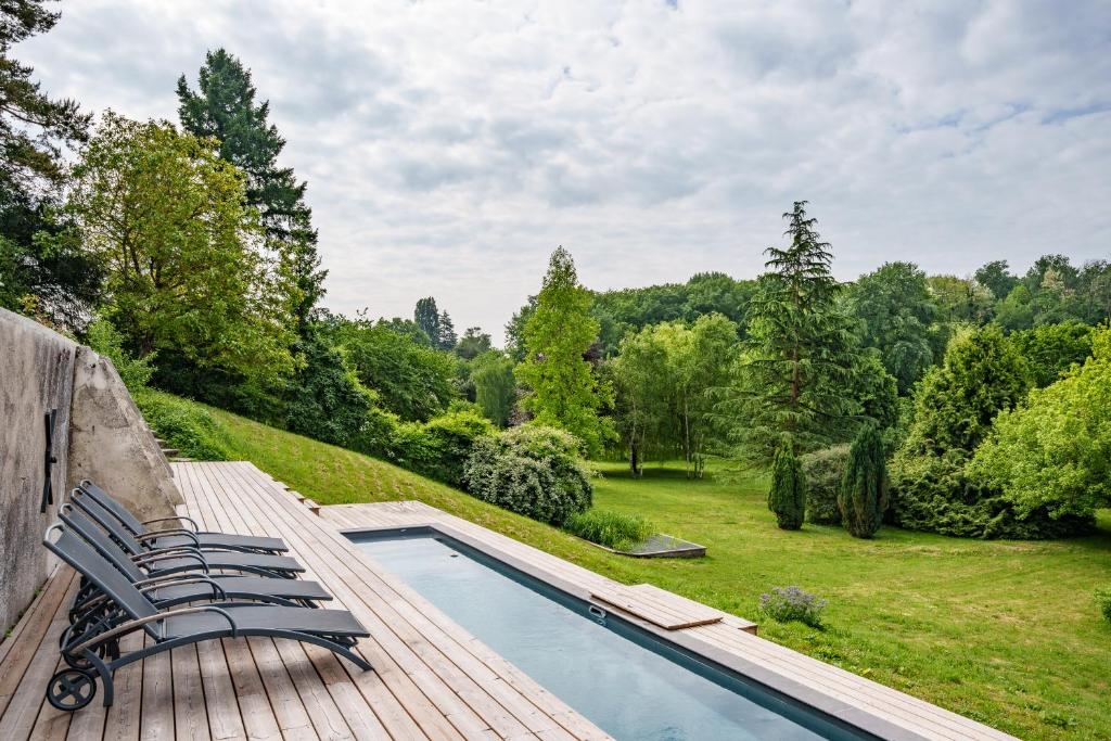 a group of chairs sitting on a deck next to a swimming pool at Élégante longère, piscine entre Tours et Amboise in Vernou-sur-Brenne