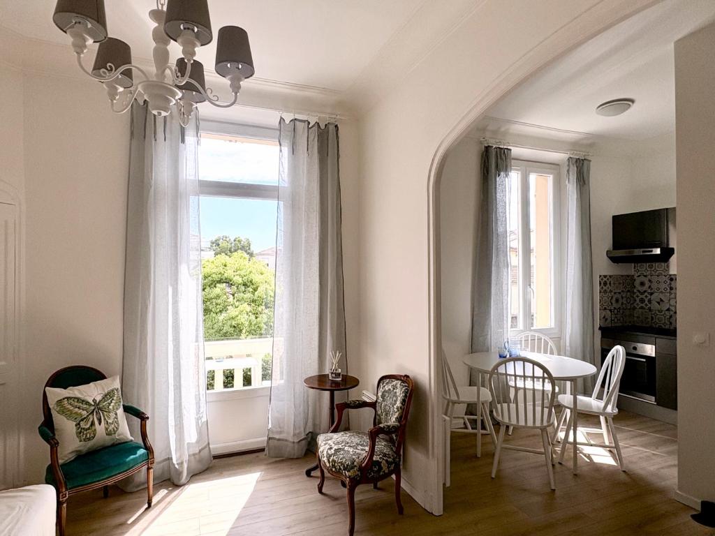 un salon avec une table et des chaises et une fenêtre dans l'établissement Cannes 2rooms app 9 min Festival -balcon-wifi, à Cannes