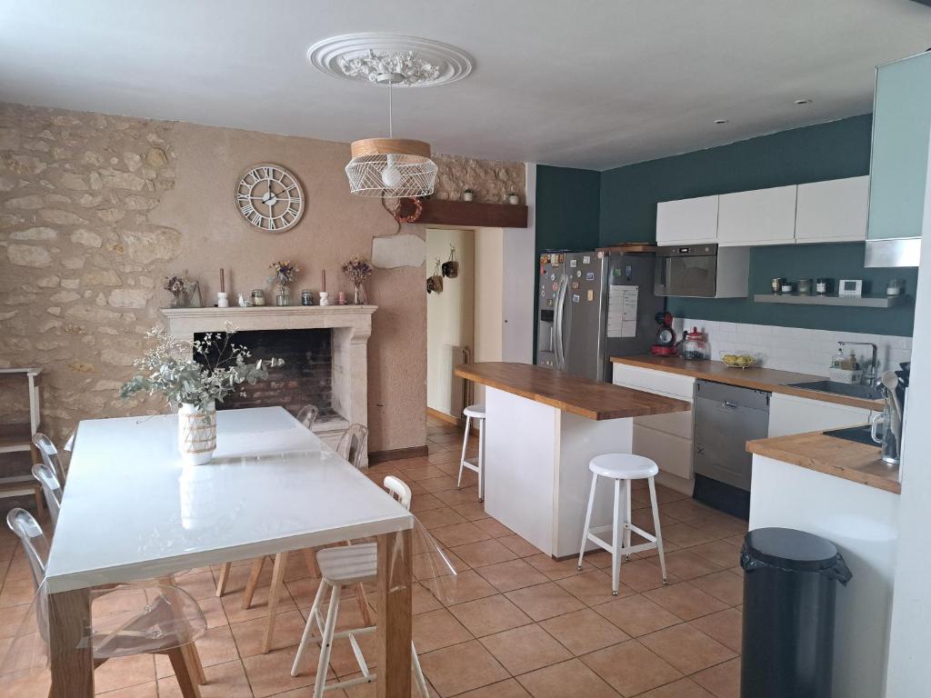a kitchen with a white table and a fireplace at maison 3 chambres 24h le mans in Le Mans