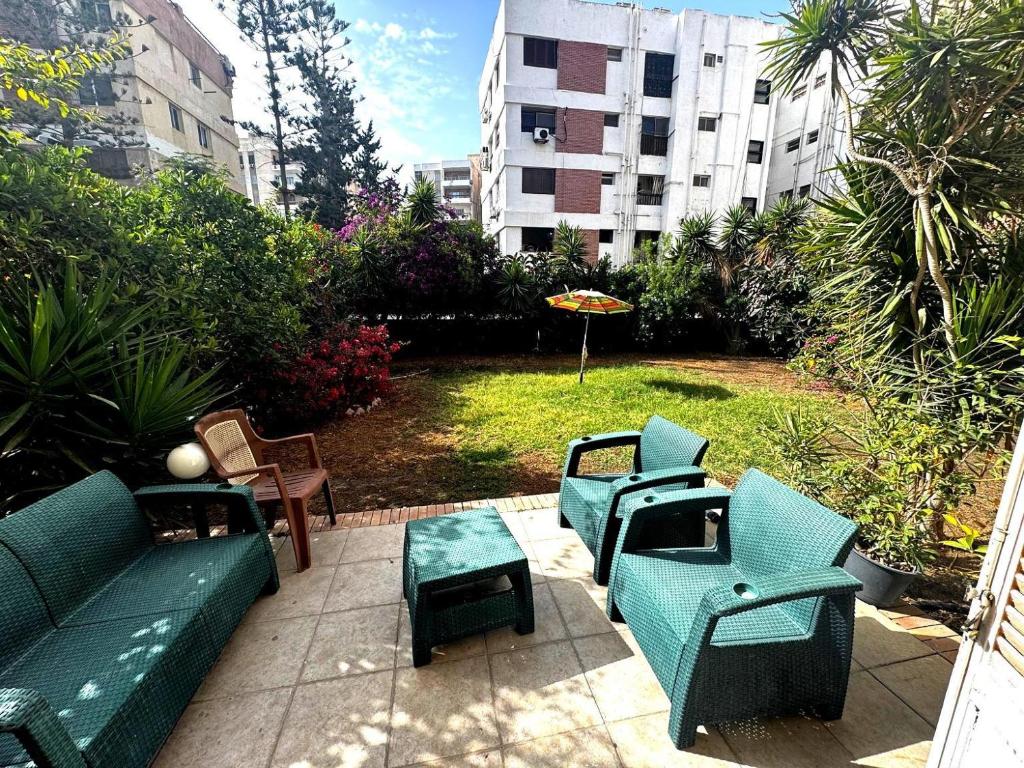 a patio with blue chairs and tables and a park at شقة غرفتين نوم بحديقة خاصة في المعمورة الشاطئ دور أرضي in Alexandria