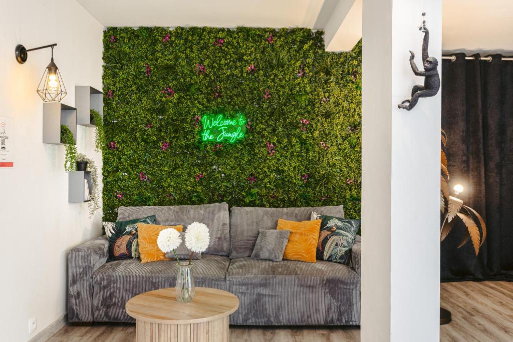 a living room with a couch and a green wall with flowers at Jungle Saintaise - Coeur de ville, Calme, Tv 4K, Fibre, Netflix, Parking Surveillé Qpark 150m in Saintes