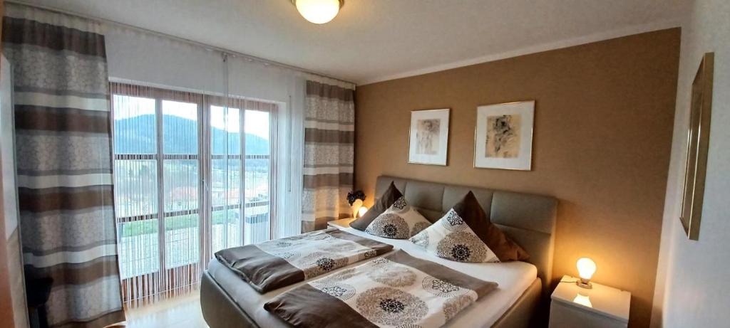 a bedroom with a bed and a large window at Ferienwohnung Harlachbergblick 1-Activ Card in Bodenmais