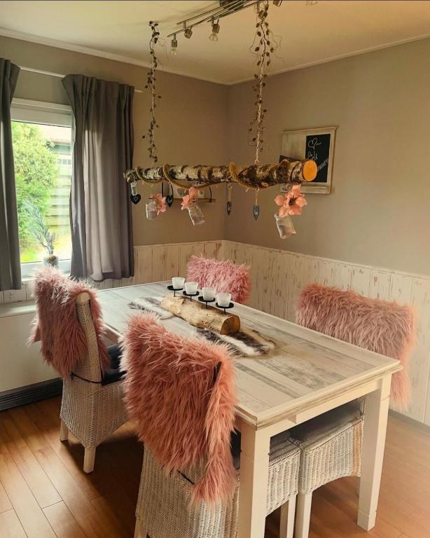 a dining room with a table with pink furry chairs at Ferienhaus "Zauberwald" mit Pelletofen & Sauna in Meschede
