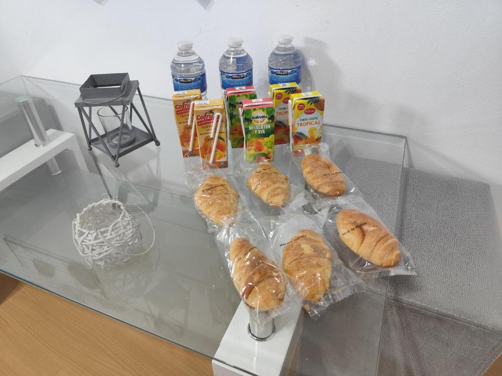 un tavolo di vetro con un mucchio di pasticcini e bottiglie d'acqua di HABITACIÓN triple con baño compartido LOVELY SEVILLA a Camas