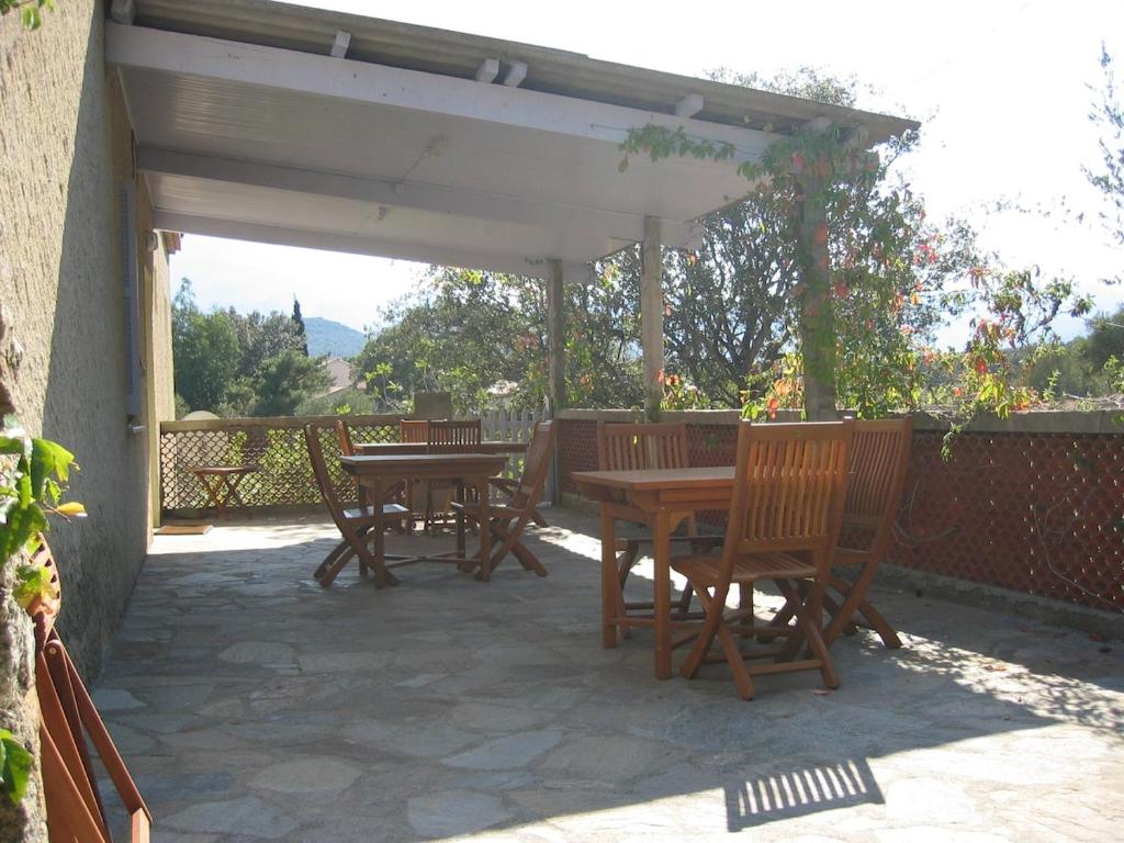 un patio avec des tables et des chaises en bois sous un pavillon dans l'établissement Appartement 2 à Regino Speloncato pour 3 personnes, à Speloncato