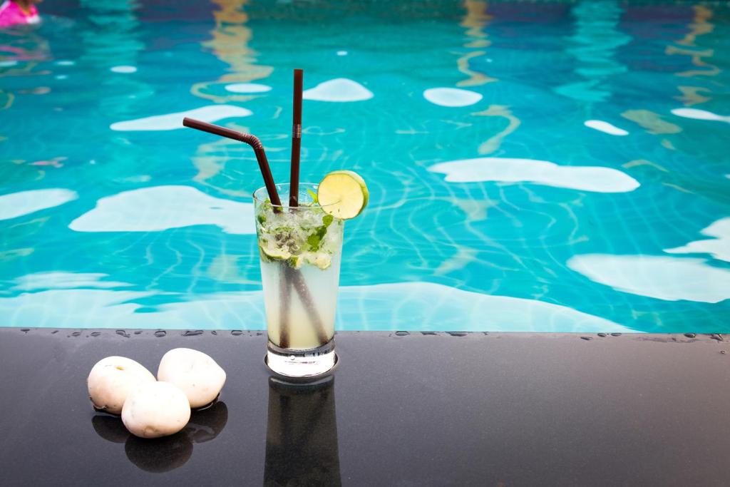 a drink sitting next to a swimming pool at Swiss Flora Royal Hotel Riyadh in Riyadh