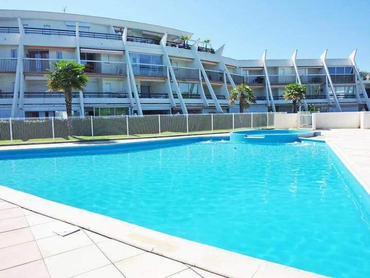 une grande piscine bleue devant un immeuble dans l'établissement Mer et soleil LGM, à La Celle-sous-Gouzon