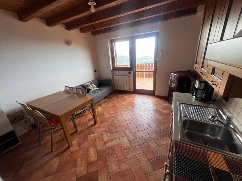 a kitchen and living room with a table and a couch at Relax con vista in Costa Valle Imagna