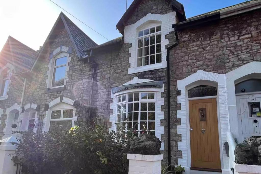 a stone house with a brown door at Charming 3-Bed Cottage - Private Garden & Parking in Torquay