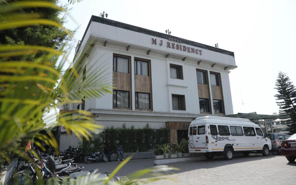 een witte bus geparkeerd voor een gebouw bij Hotel MJ Residency in Dehradun