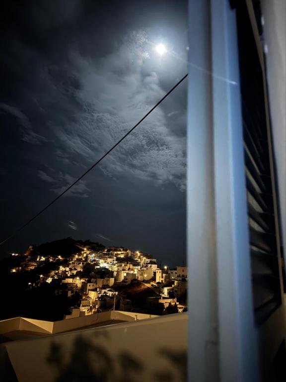 a view of a city at night with the moon at Houses of chora in Serifos Chora