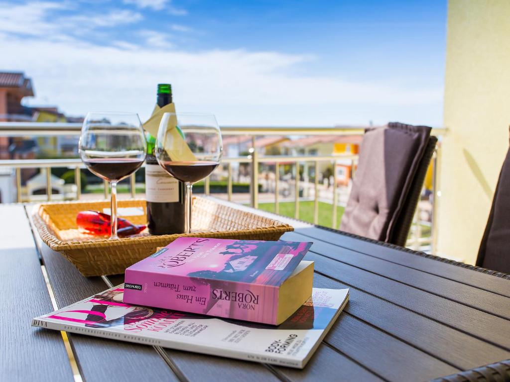 ein Buch und eine Weingläser auf dem Tisch in der Unterkunft Apartment Maestral in Poreč