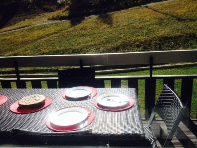 une table avec quatre assiettes dessus sur un balcon dans l'établissement Cozy Duplex Terrasse plein sud, à Puy-Saint-Vincent