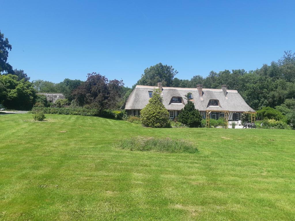 une maison sur un terrain herbeux avec une cour dans l'établissement Chambres d'hôtes Le Clos des Chaumes, proche Honfleur, à Saint-Maclou