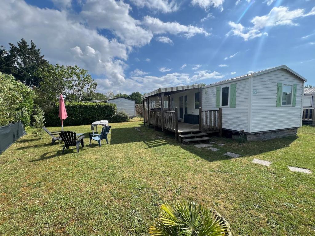 une petite maison dans une cour avec une table et des chaises dans l'établissement 421 Mobil home domaine de la forge, à La Teste-de-Buch